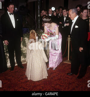 La regina Elisabetta II si stira a ricevere un bouquet da Amanda Jane Smythe, che appare come il bambino Elizabeth nel film 'Anne of a Thousand Days', al Royal Film Performance at the Odeon, Leicester Square, Londra. Foto Stock