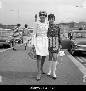 Welsh Singer Shirley Bassey raffigurato con la figlia Sharon (12) all'aeroporto di Heathrow. Dovevano imbarcarsi su un volo per Monte Carlo per assistere ad uno spettacolo di gala, seguito da una vacanza a Monaco. Shirley indossa un cappotto bianco e una berretto gay a strisce di caramelle. Foto Stock