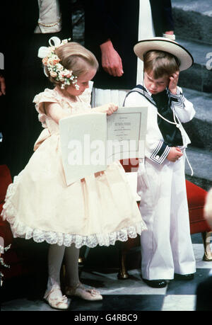 Laura Fellowes (a sinistra) di sei anni mostra il suo cugino di tre anni Principe William, figlio del Principe e della Principessa del Galles, un'entrata nel foglio dell'Ordine del Servizio durante la cerimonia nuziale della sig.ra Sarah Ferguson e del Duca di York all'Abbazia di Westminster. Foto Stock