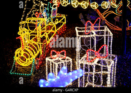 Un treno e presenta sono tra le sculture di luce di corda seduto nel giardino in una casa semi-indipendente su Longford Road, Melksham, Wiltshire, come è illuminato da luci di Natale e decorazioni come alcune famiglie nel Regno Unito entrano nello spirito di festa. Foto Stock