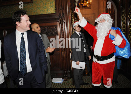 Il cancelliere George Osborne (a sinistra) ride al cancelliere ombra ed Balls (a destra) vestito da Babbo Natale in una festa di Natale per i bambini dei parlamentari nella Camera dei Comuni, Londra. Foto Stock