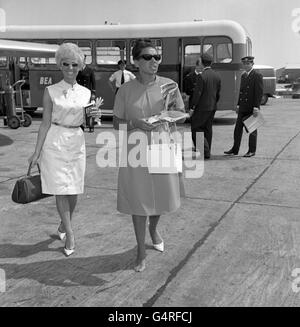 La cantante Shirley Bassey, che recentemente ha scattato e perso la sua scarpa all'aeroporto di Londra, ha avuto problemi simili oggi quando il suo tallone catturato, e bloccato veloce nel catrame sciogliente sul grembiule a Heathrow. Senza scoraggiarsi, camminava, con una sola scarpa. È stata a Palma, dove sta comparendo nel Club di Titos. Foto Stock