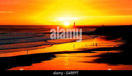 La gente cammina sulla spiaggia durante l'alba su Tynemouth Longsand, a Tynemouth, Tyne e indossare. Foto Stock