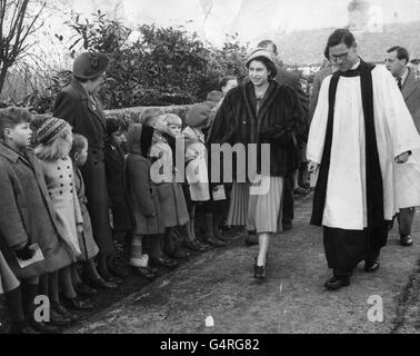 La regina Elisabetta II sorride ai bambini del villaggio che la salutarono quando arrivò alla chiesa parrocchiale di Mersham. La Regina è accompagnata dal Rettore di Mersham, il Rev. J. Edinger, che ha condotto il servizio. Foto Stock