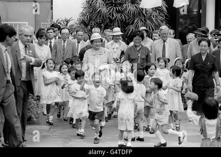 La Regina Elisabetta II è circondata da bambini cinesi entusiasti con il Segretario del Commonwealth Sir Geoffrey Howe, Right, e un interprete tra loro, dopo un concerto di 300 bambini al Palazzo dei Bambini di Canton. Sullo sfondo, quarto da sinistra, è il soprintendente capo Jim Beaton, l'ufficiale della polizia della Regina, e primo piano, secondo a sinistra, il Segretario della Stampa Michael Shea. Foto Stock