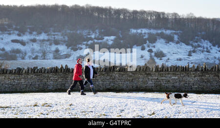 Gli escursionisti e i loro cani ammirano la vista dal Crickley Hill Country Park, Gloucestershire, come il paese si è bracchiato per un periodo di tempo più fresco che ha portato la neve in alcune regioni. Foto Stock