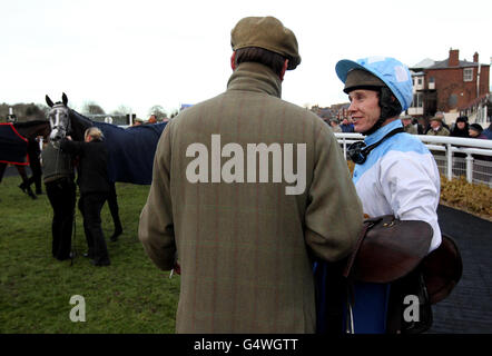 Jockey Richard Johnson parla con l'allenatore Henry Daley dopo la vittoria su Artic ben nel Contract Fire and Security Handicap Chase alle corse di Warwick. Foto Stock