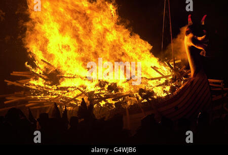 La 'squadra Jarl' di guizzatori - Shetlanders vestita in costume vichingo - incendia la Galley, una longship di legno di 30 piedi, mentre canta la 'Casa del Norseman' a Lerwick, Shetland Isles, come parte del tradizionale festival pagano di Up Helly AA. * Up Helly AA ha avuto origine come festival pagano del Norse e poi è stato adottato dai cristiani per celebrare la fine del periodo santo cristiano con il digiuno e i falò. Foto Stock