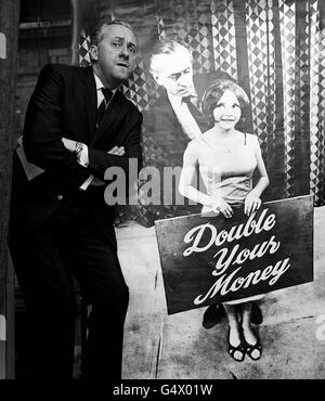 Il Quizmaster Hughie Green si pone a Londra con un poster di se stesso e dell'assistente Monica Rose, per presentare la borsa di studio Travel Research del programma TV 'Double Your Money'. Foto Stock