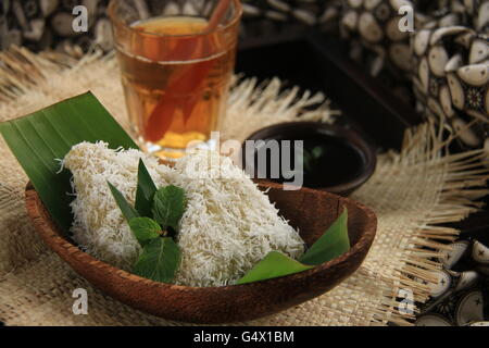 Lupis, tradizionale Giavanese riso glutinoso torta con cocco grattugiato e palm sciroppo di zucchero. Placcata in contemporanea set giavanese. Foto Stock