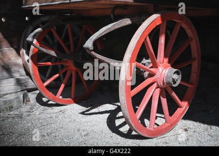 Frammento di un vecchio carrello di legno con ruote rosse Foto Stock