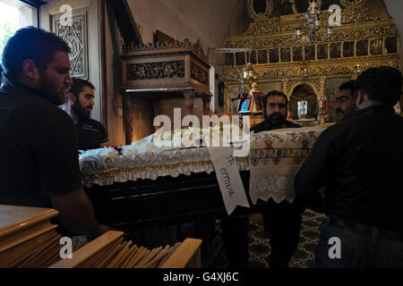 Gli uomini portano una bara nella chiesa di Agios Ioannis per una cerimonia funebre in Anogia, sull'isola di Creta in Grecia Foto Stock