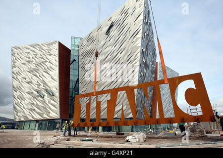 AUTONOMO: Il cartello in acciaio da 15 tonnellate del Titanic Belfast, ritenuto il più grande mai costruito in Irlanda del Nord, è abbassato in posizione davanti al nuovo edificio Titanic Signature. Foto Stock