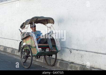 Indonesia, Java, Yogyakarta, scene di strada - dormire rickshaw conducente Foto Stock