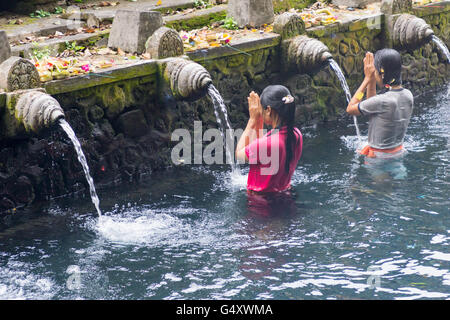 Indonesia, Bali, Gianyar, pregando le donne nell'acqua del tempio indù Pura Tirta Empul Foto Stock