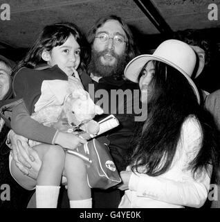 John Lennon, detiene Kyoko Cox, la figlia di 6 anni di sua moglie giapponese, Yoko Ono, all'arrivo del bambino all'aeroporto di Heathrow, dove aveva volato da New York. Foto Stock