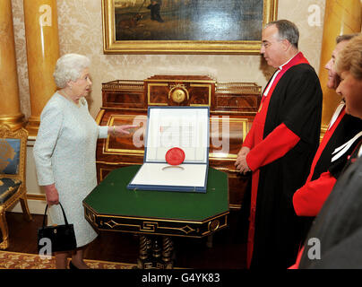 Regina Elisabetta II con il Decano di Westminster Abbey Dr John Hall (seconda a sinistra) e altri membri del personale Abbey, in quanto presenta una carta storica che illustra come l'Abbazia dovrebbe essere governata giorno per giorno, durante un pubblico privato a Buckingham Palace nel centro di Londra. Foto Stock