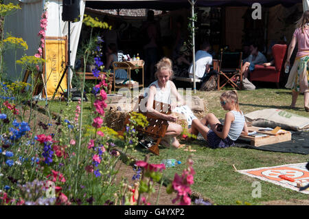 Famiglie sulla festa di balle di fieno di fronte entertainment tende al porto Eliot Festival Cornovaglia Foto Stock