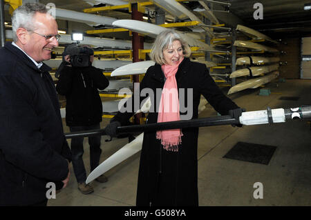 Il segretario di casa Theresa May è mostrato attrezzature per canottaggio nella sala da boathouse da Ivor Lloyd, direttore generale di Eton Dorney Lake durante un tour della sede olimpica. Foto Stock