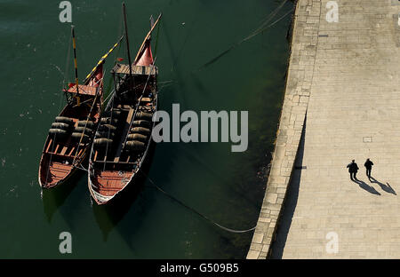 La gente passa accanto a Port Wine Boats ormeggiate sul fiume Douro sul lungomare di Porto, Portogallo Foto Stock