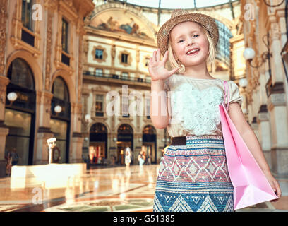 Scopri le più inaspettate tendenze a Milano. Ritratto di felice moda ragazza con rosa shopping bag lato sventolando in Galleria Vittorio Emanuele II Foto Stock