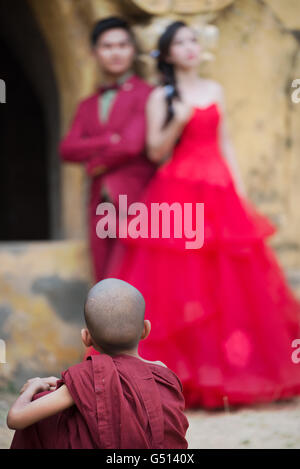 Un monaco novizio guardando un solo una coppia sposata in posa, Maha Aung Mye Bonzan Kyaung Monastero, Mingun, Sagaing Regione, Myanmar Foto Stock