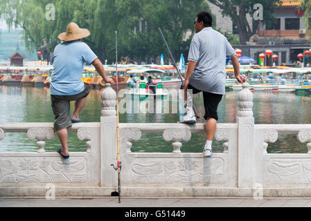 Cina, Pechino, Due pescatori al Waterfront al Lago Qianhai, scena (pedale barca e pescatori) al Lago Qianhai Foto Stock