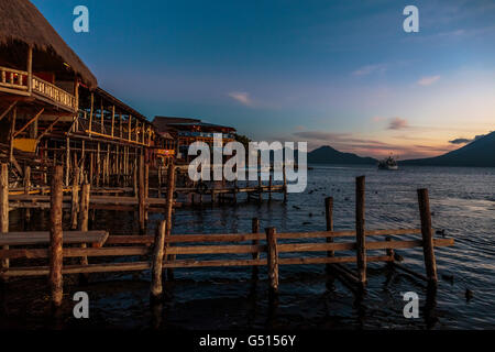 Il sole tramonta sul Lago de Atitlan in Guatemala e i turisti e i locali raccogliere dal molo di Panajachel come ultimo barche provengono Foto Stock