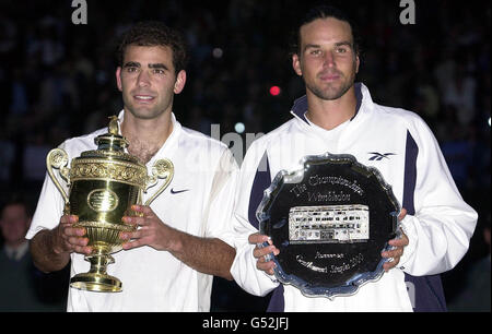 NESSUN USO COMMERCIALE: L'America's Pete Sampras detiene il trofeo mentre celebra la sua vittoria del 6/7 7/6 6/4 6/2 su Pat Rafter australiano (a destra) per vincere la finale maschile di Singles a Wimbledon. Foto Stock