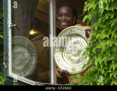 NESSUN USO COMMERCIALE: Venus Williams, campionessa delle Signore di Wimbledon, mette in posa da una finestra per i fotografi, mentre celebra la vittoria del trofeo Ladies Singles e del trofeo Ladies Doubles ai Campionati di Tennis sul prato a Wimbledon. * Venus ha vinto il trofeo Ladies Singles sconfiggendo Lindsay Davenport in finale e ha vinto il doppio con la sorella minore Serena. Foto Stock