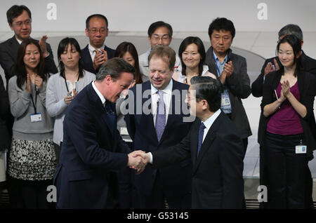 Il primo Ministro David Cameron stringe le mani con il Chief Operating Officer Toshiyuki Shiga come Vice Presidente Esecutivo Andy Palmer (al centro) guarda durante una visita alla sede centrale di Nissan a Tokyo, Giappone. Foto Stock