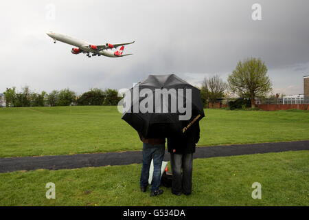 Gli appassionati di volo osservano un aereo della Virgin Atlantic decollo dall'aeroporto di Heathrow sotto la pioggia. Foto Stock