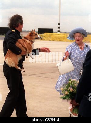 1990: Un calciatore della famiglia reale sulla asfalto dell'aeroporto di Heathrow di Londra, che porta uno dei corgis della Regina Madre, restituendo la borsa della Regina Madre al suo proprietario. Foto Stock
