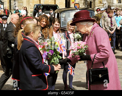 La regina Elisabetta II è data fiori ai bambini delle scuole locali durante una passeggiata nel centro di Windsor, dopo la partenza dal Castello di Windsor con il Duca di Edimburgo. Foto Stock