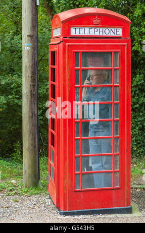 Uomo che utilizza un vecchio stile Britannico rosso nella casella Telefono. Foto Stock