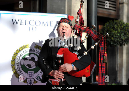 Un giocatore di cornamusa accoglie gli ospiti alla cerimonia di premiazione all'esterno Il Grosvenor House Hotel Foto Stock