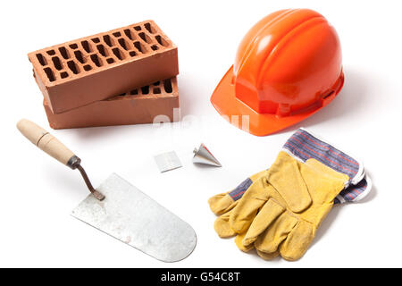 Diversi accessori di costruzione cazzuola, mattoni, Piombino, elmetto e guanti isolati su sfondo bianco. Foto Stock