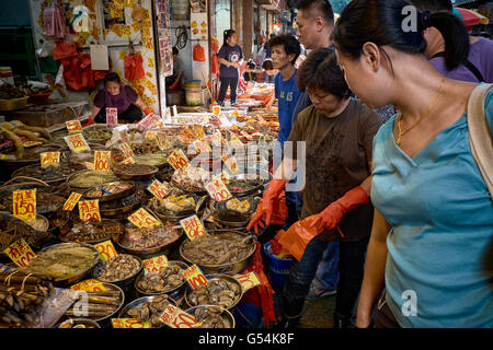 Gli amanti dello shopping si riuniscono intorno e fare acquisti in un guscio di pesce di stallo fornitori su Nelson Street a Mongkok, Hong Kong. Foto Stock