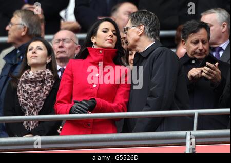 Il proprietario di Liverpool John W. Henry parla con sua moglie Linda Pizzuti (centro a sinistra) negli stand Foto Stock