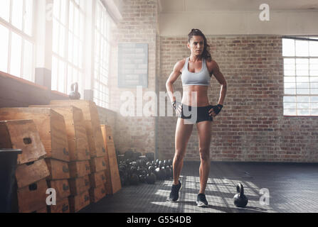 A piena lunghezza shot di determinata donna fitness walking nella palestra crossfit. Sportive muscolare in fase di riscaldamento prima di una intensa worko Foto Stock