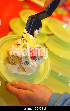 Torta dolce con la panna montata e la frutta fresca e la mano dello chef Foto Stock