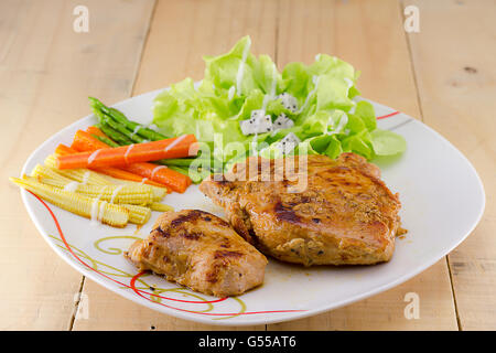 Le bistecche grigliate sul piatto bianco con insalata Foto Stock