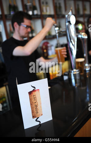 Un barman versa una pinta di birra a mezzogiorno Enoteca al Lingfield Park racecourse Foto Stock