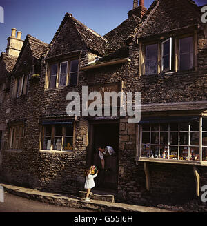 LACOCK c1954: Un negoziante si affaccia sulla porta stalla a mano una bambina un mazzo di fiori nel villaggio del North Wiltshire di Lacock, nr Chippenham. Il villaggio, ora di proprietà del National Trust, vanta l'architettura di ogni secolo dal 13, tra cui l'abbazia di Lacock, fondata nel 1232. Foto Stock