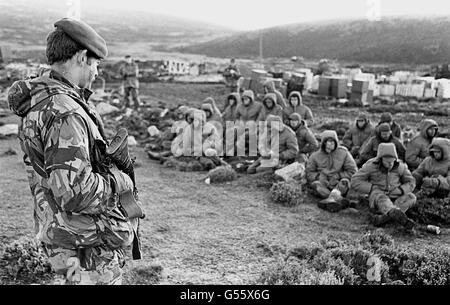 LA GUERRA DELLE FALKLANDS 1982: I soldati argentini catturati a Goose Green sono custoditi da un Royal Marine britannico mentre attendono il transito fuori dalla zona. Goose Green è stato catturato da uomini del reggimento dei paracaduti, parte della task force britannica. 825/03/02 i soldati argentini catturati a Goose Green sono custoditi da un Royal Marine britannico mentre attendono il transito fuori dall'area. Il 20° anniversario dell'invasione delle Falklands da parte delle forze argentine sarà il 2 aprile 2002. Foto Stock