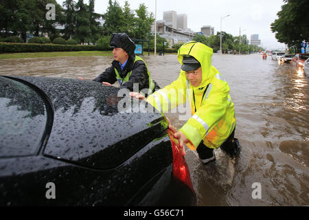 Huzhou, cinese della Provincia di Zhejiang. Xx Giugno, 2016. Poliziotti del traffico spingere un auto su una strada di Huzhou, est della Cina di Provincia dello Zhejiang, 20 giugno 2016. Piogge torrenziali che hanno colpito la città di domenica sera, causando waterlogging nel centro cittadino di aree. Le precipitazioni giornaliere ha stabilito un nuovo record con 227.2 millimetri da 6 p.m. Lunedì. Credito: Zhang Jian/Xinhua/Alamy Live News Foto Stock