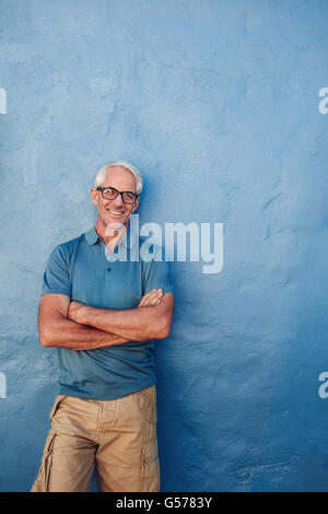 Ritratto di un sorridente uomo maturo in piedi con le braccia incrociate. Caucasian uomo di mezza età che guarda lontano a copiare lo spazio e smilin Foto Stock