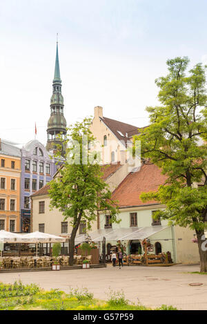 RIGA, Lettonia - GIUGNO 10,2016: una strada del centro storico di Riga. In fondo è il campanile di San Pietro Churc Foto Stock