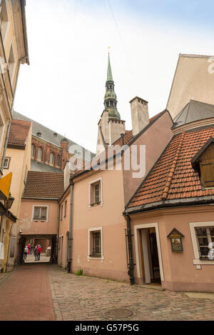 RIGA, Lettonia - GIUGNO 10,2016: una strada del centro storico di Riga. In fondo è il campanile di San Pietro Churc Foto Stock