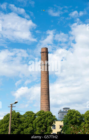 Un elicottero che vola su un vecchio invecchiato weathered tall industriale camino in fabbrica Foto Stock